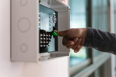 An employee using a biometric access control system to enter a room via their fingerprint